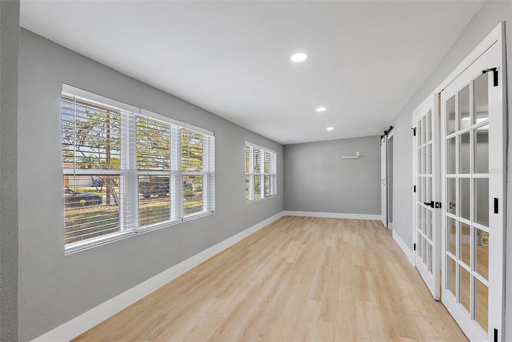 A sunroom with light wood-look flooring, gray walls, recessed lighting, and white French doors — 3926 HELENA STREET NE, ST PETERSBURG, FL