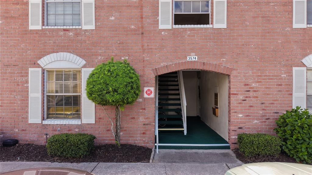 A brick building exterior features a ground-level arched entryway with stairs leading to upper units — 3574 41ST AVENUE S UNIT 149, ST PETERSBURG, FL