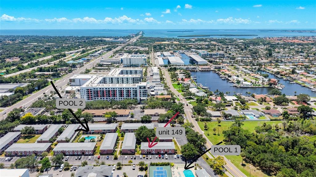 This aerial view shows a multi-story apartment complex with two swimming pools and parking lots — 3574 41ST AVENUE S UNIT 149, ST PETERSBURG, FL