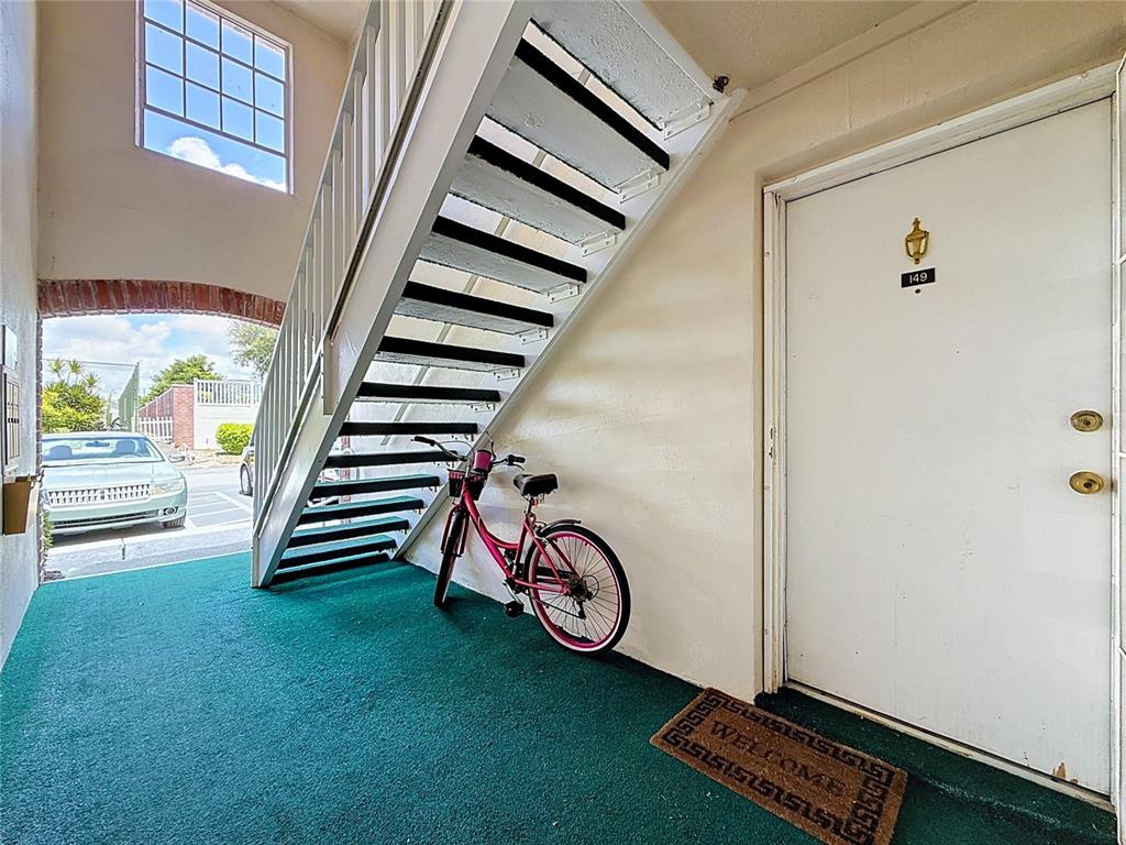 An outdoor staircase leads to a white door with a bicycle parked underneath — 3574 41ST AVENUE S UNIT 149, ST PETERSBURG, FL