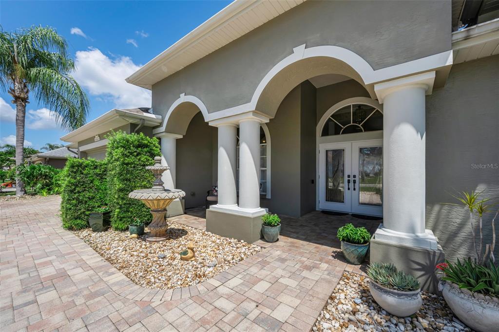 The exterior of a house features a paved walkway, a fountain, and white columns — 8843 BEL MEADOW WAY, TRINITY, FL