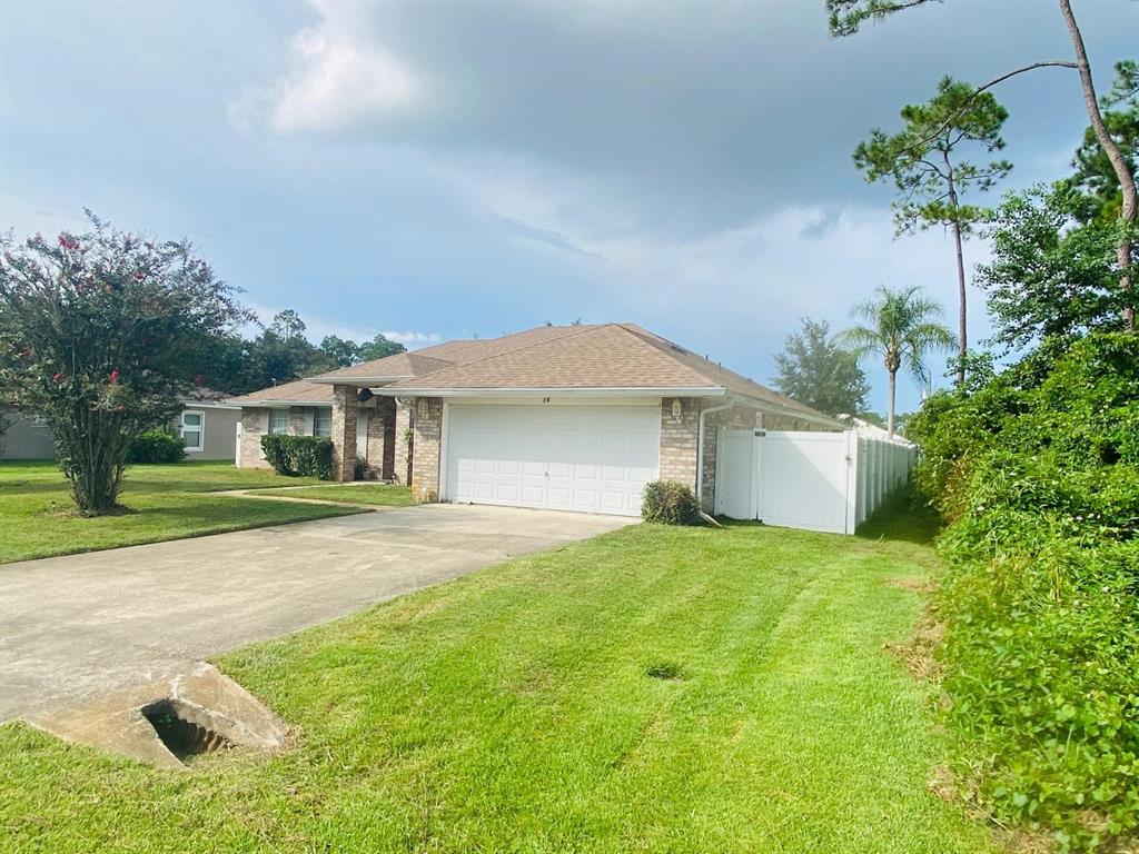 A single-story brick house with a two-car garage and a white vinyl fence — 16 RED BARN DRIVE, PALM COAST, FL