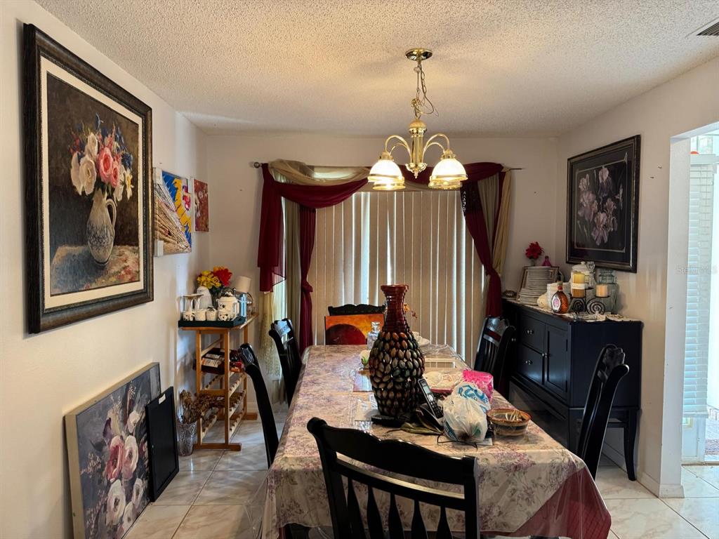 A dining room features a long table, a chandelier, wall art, and a dark sideboard — 16 RED BARN DRIVE, PALM COAST, FL