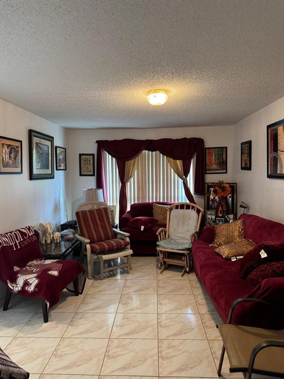 A living room features tile flooring, a red sofa, two armchairs, and a window with curtains — 16 RED BARN DRIVE, PALM COAST, FL