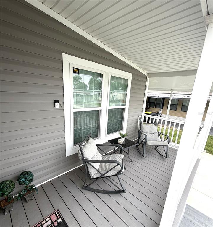 A covered porch features gray siding, a double window, and two rocking chairs — 118 JANA CIRCLE, AUBURNDALE, FL