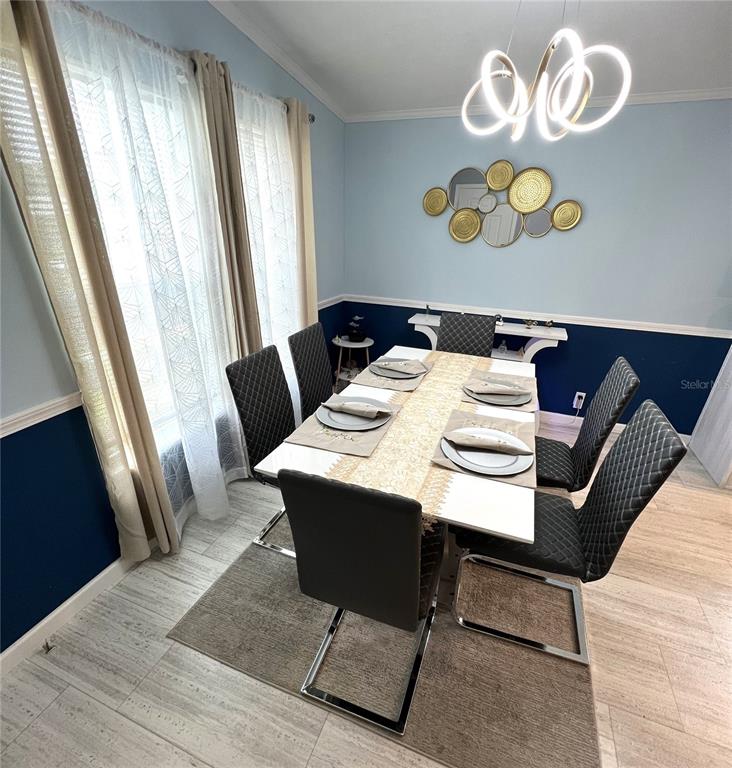 A dining room features a white table with six black chairs and a modern chandelier — 118 JANA CIRCLE, AUBURNDALE, FL