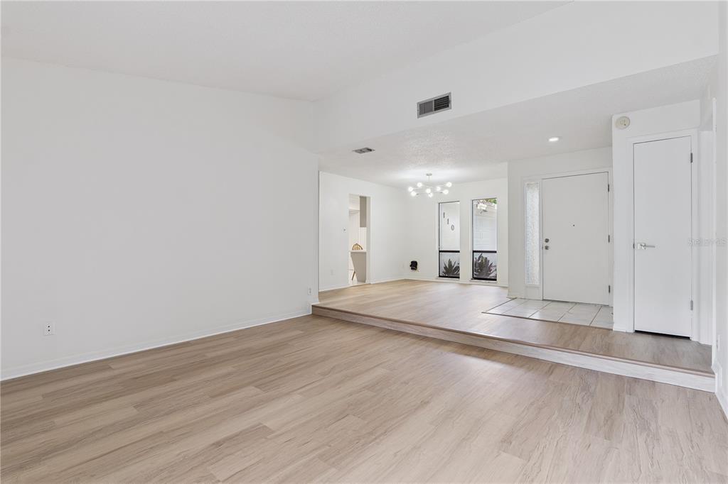 A sunken living room features light wood-look flooring, white walls, and an elevated entryway area — 110 HOLDERNESS DRIVE, LONGWOOD, FL