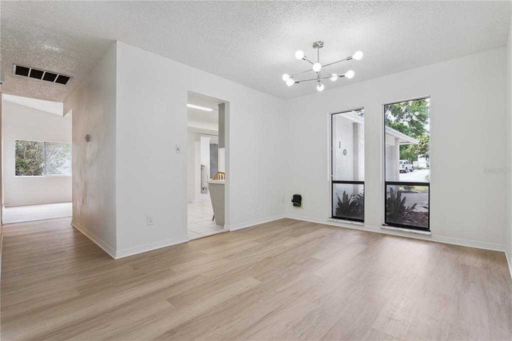 A bright dining room features light wood-look flooring, white walls, and a modern sputnik chandelier — 110 HOLDERNESS DRIVE, LONGWOOD, FL