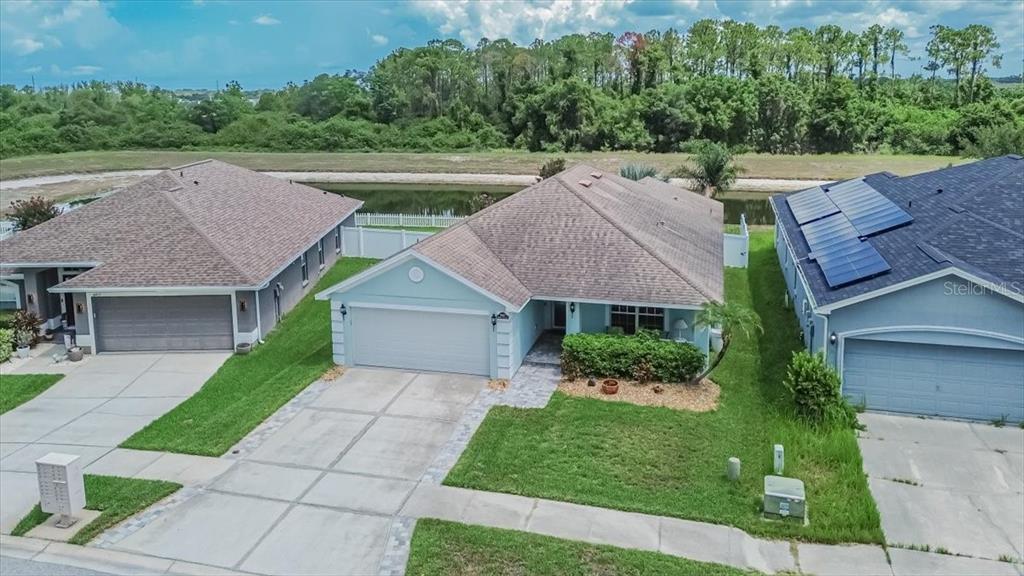 An aerial view shows three suburban houses with driveways and a pond in the background — 14415 BARLEY FIELD DRIVE, WIMAUMA, FL
