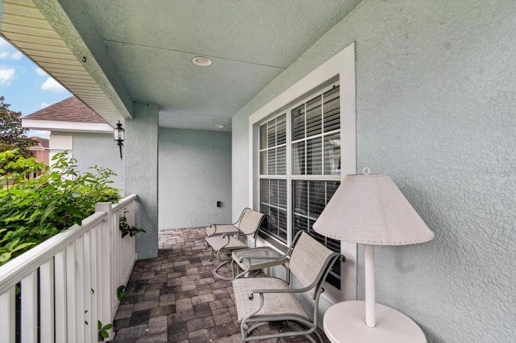 A covered patio features light blue stucco walls, a paver floor, and outdoor seating — 14415 BARLEY FIELD DRIVE, WIMAUMA, FL