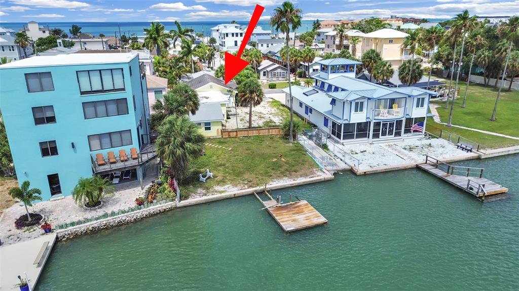 An aerial view of a vacant waterfront lot featuring a wooden dock and surrounding houses — 201 90TH AVENUE, TREASURE ISLAND, FL