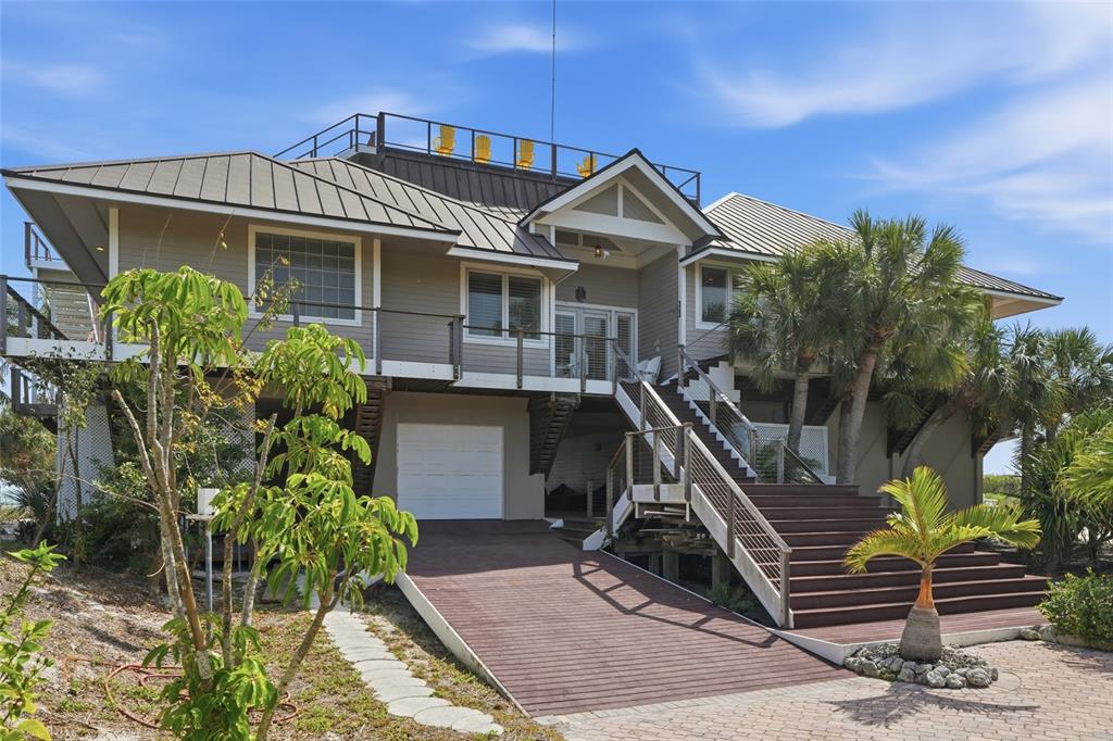 A stilt house with a metal roof, wooden deck, stairs, and a rooftop viewing area — 211 KINGFISHER DRIVE, CAPTIVA, FL