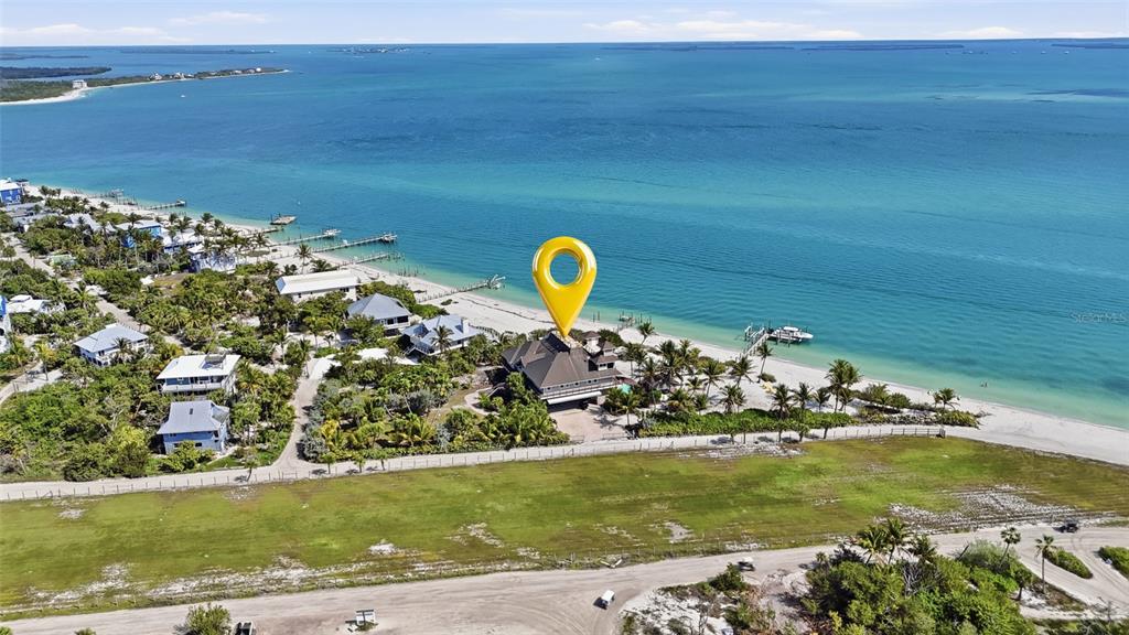 An aerial view shows a beachfront house with a yellow location pin on the roof — 211 KINGFISHER DRIVE, CAPTIVA, FL