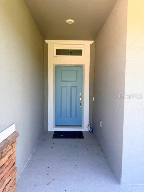 A blue front door is set within a recessed entryway with gray walls and flooring — 2840 MONAGHAN DRIVE, ORMOND BEACH, FL