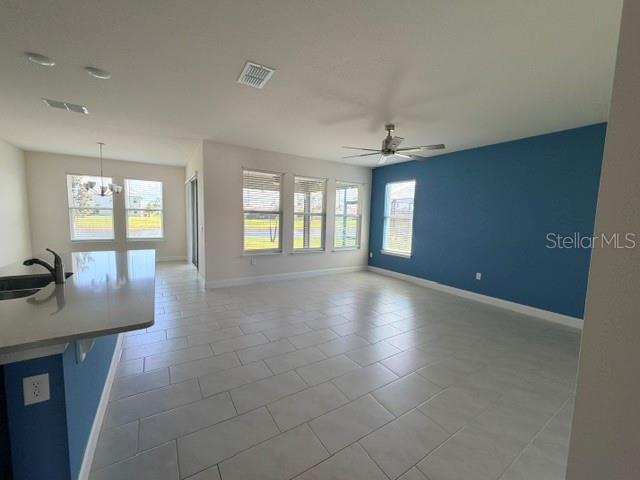 A living area with light tile floors, a blue accent wall, and a ceiling fan — 2840 MONAGHAN DRIVE, ORMOND BEACH, FL