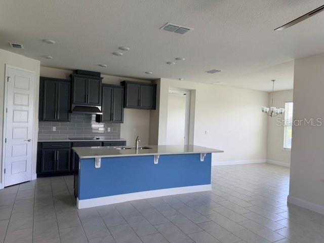 A kitchen features dark cabinets, a blue island with a countertop, and light tile flooring — 2840 MONAGHAN DRIVE, ORMOND BEACH, FL
