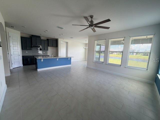 An open-concept kitchen with dark cabinets and a blue island overlooks a spacious living area — 2840 MONAGHAN DRIVE, ORMOND BEACH, FL