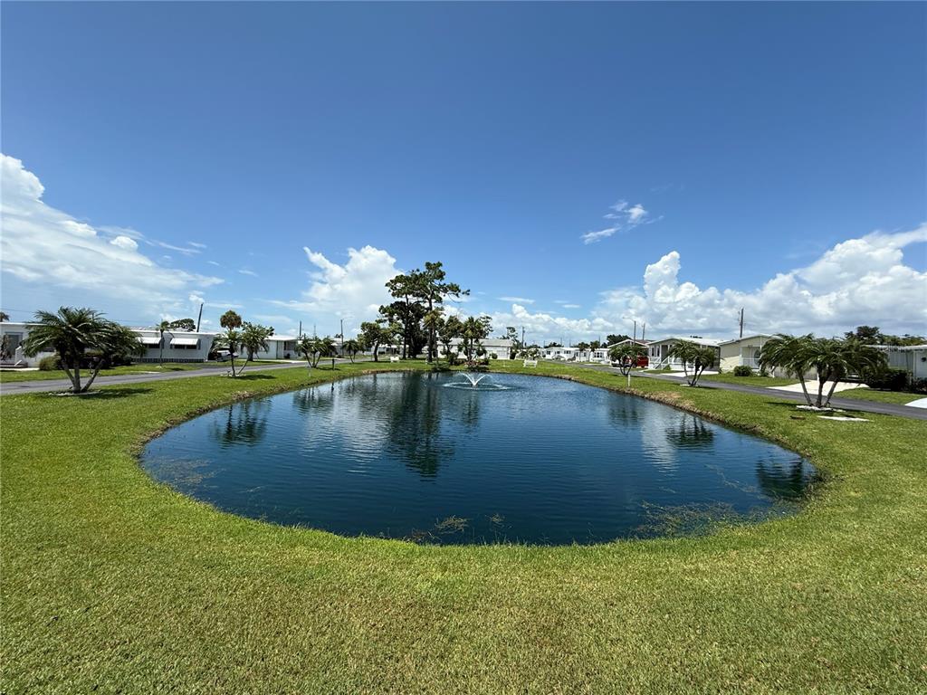 An outdoor swimming pool with a brick paver deck and lounge chairs under a blue sky — 231 INNER DRIVE E, VENICE, FL