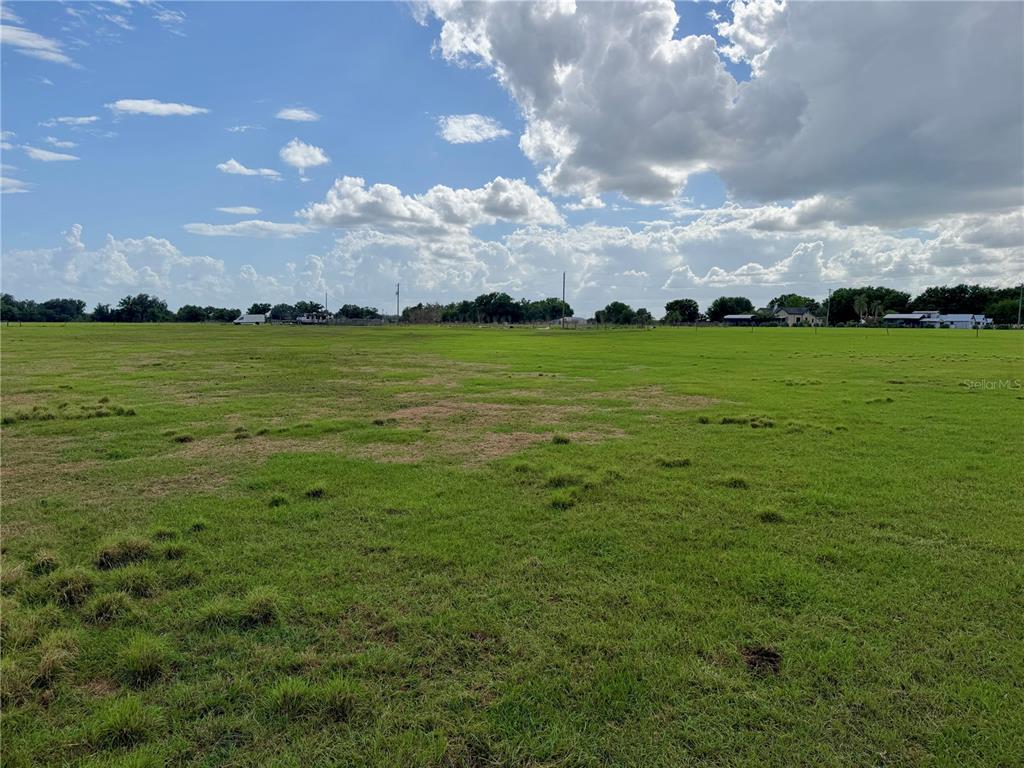 A fenced outdoor enclosure stands in a grassy field near a parked travel trailer — W ST RD 64, WAUCHULA, FL