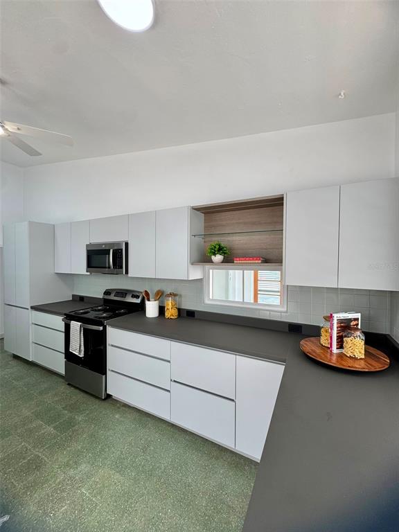 A modern kitchen features white flat-panel cabinets, dark gray countertops, and a green tiled floor — F-6 CALLE GENOVA UNIT F-6, GUAYNABO, PR