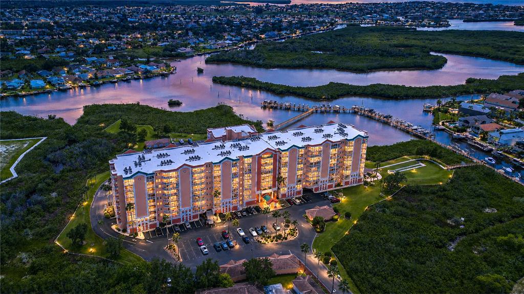 An aerial view shows a large multi-story apartment building surrounded by mangroves and a waterway — 4516 SEAGULL DRIVE UNIT 318, NEW PORT RICHEY, FL