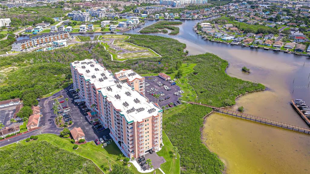 An aerial view shows a multi-story residential building surrounded by parking lots, vegetation, and water — 4516 SEAGULL DRIVE UNIT 318, NEW PORT RICHEY, FL