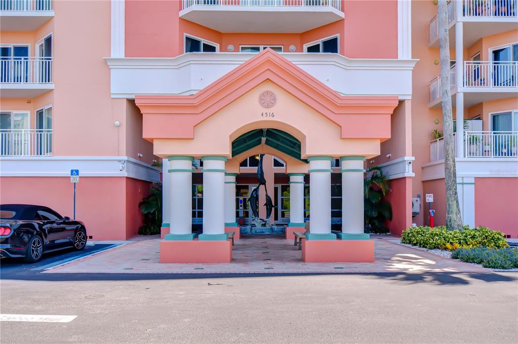 The exterior of a peach-colored multi-story building features a covered entrance with white columns — 4516 SEAGULL DRIVE UNIT 318, NEW PORT RICHEY, FL