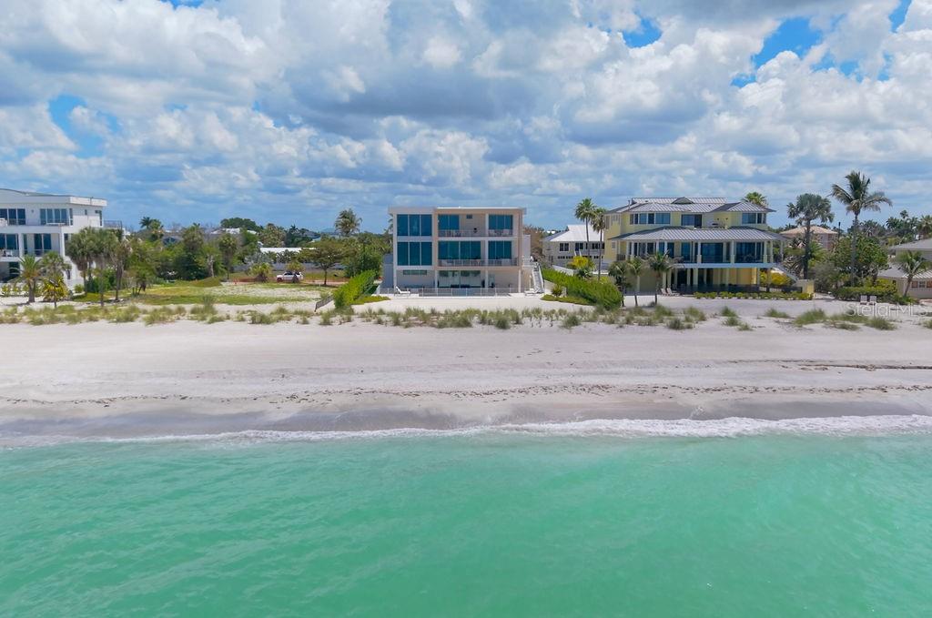 The exterior of a modern home features a glass double door, stone walls, and landscaping — 6489 GULFSIDE ROAD, LONGBOAT KEY, FL