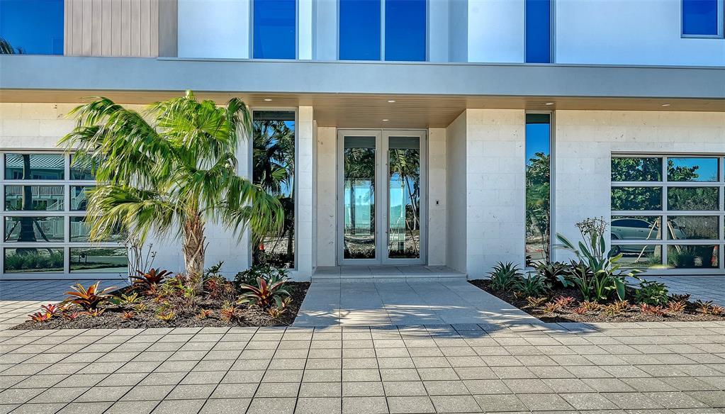 A modern three-story house features a white exterior, large windows, and a glass garage door — 6489 GULFSIDE ROAD, LONGBOAT KEY, FL