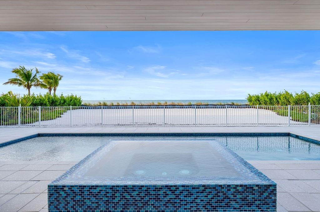 A tiled spa and swimming pool overlook a white sand beach behind a metal fence — 6489 GULFSIDE ROAD, LONGBOAT KEY, FL