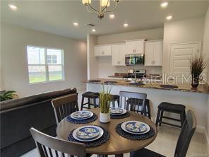 A dining area with a round table sits in front of an open kitchen with island seating — 231 BITTERN LOOP, INVERNESS, FL