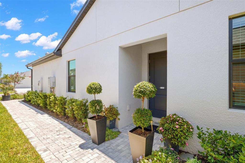 A paved walkway leads to the dark front door of a white stucco house — 5828 WINDBREAK COURT, APOLLO BEACH, FL