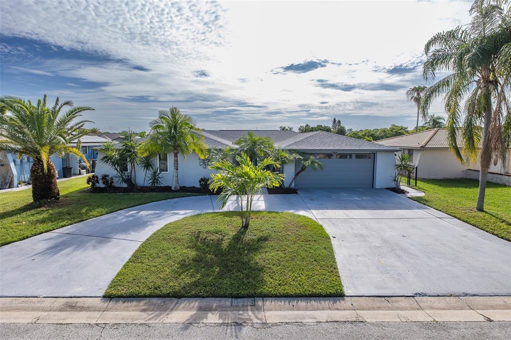 A single-story house with a gray garage, a circular driveway, and several palm trees — 9816 SAN MATEO WAY, PORT RICHEY, FL