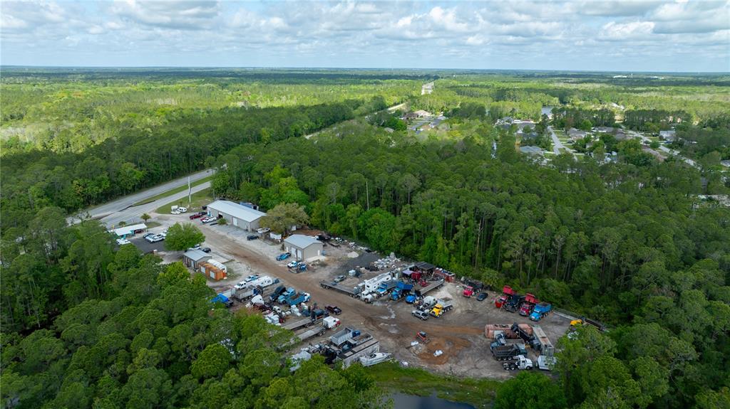 An aerial view shows a commercial lot with several buildings, trucks, and equipment amidst trees — 2270 US HIGHWAY 1, BUNNELL, FL