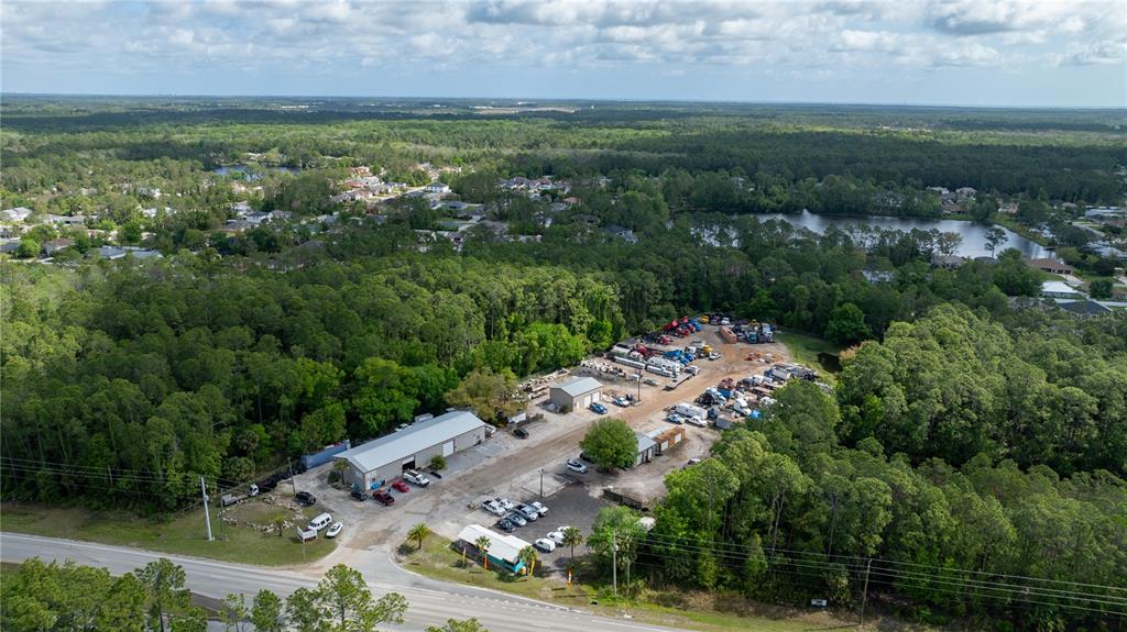 An aerial view shows a commercial property with several buildings and parked vehicles amidst trees — 2270 US HIGHWAY 1, BUNNELL, FL