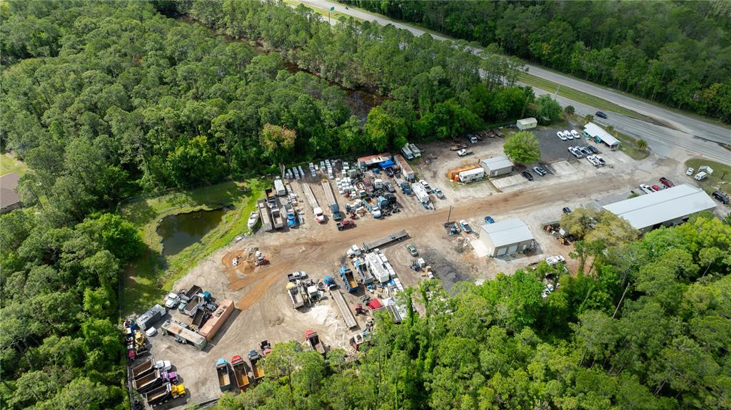 An aerial view shows a commercial storage yard with various vehicles, equipment, and metal buildings — 2270 US HIGHWAY 1, BUNNELL, FL