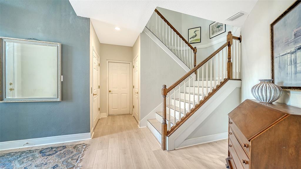 An entryway features light wood flooring, a staircase with wooden railings, and a blue accent wall — 12402 HARBOUR LANDINGS DRIVE, CORTEZ, FL