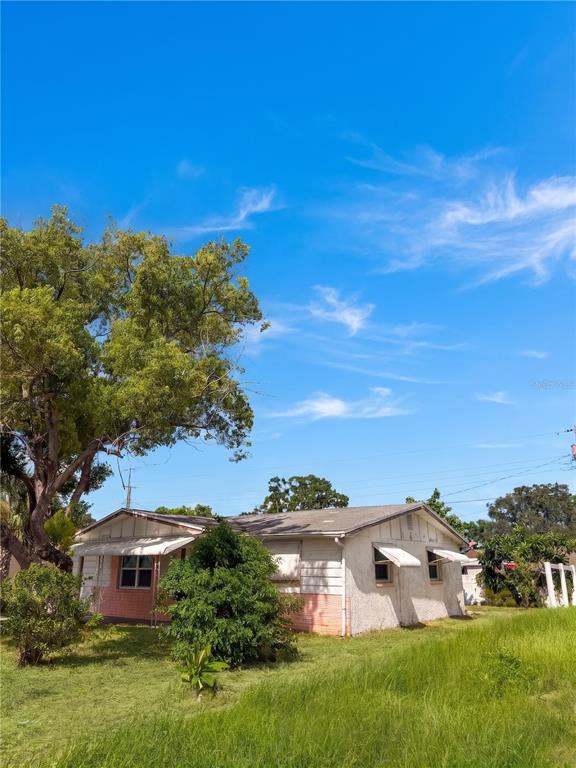 A single-story house with white siding and pink accents sits on a grassy lot — 2412 ARCADIA ROAD, HOLIDAY, FL