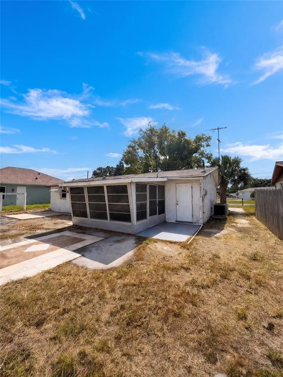 The exterior of a small house features a screened-in porch and a white door — 2412 ARCADIA ROAD, HOLIDAY, FL