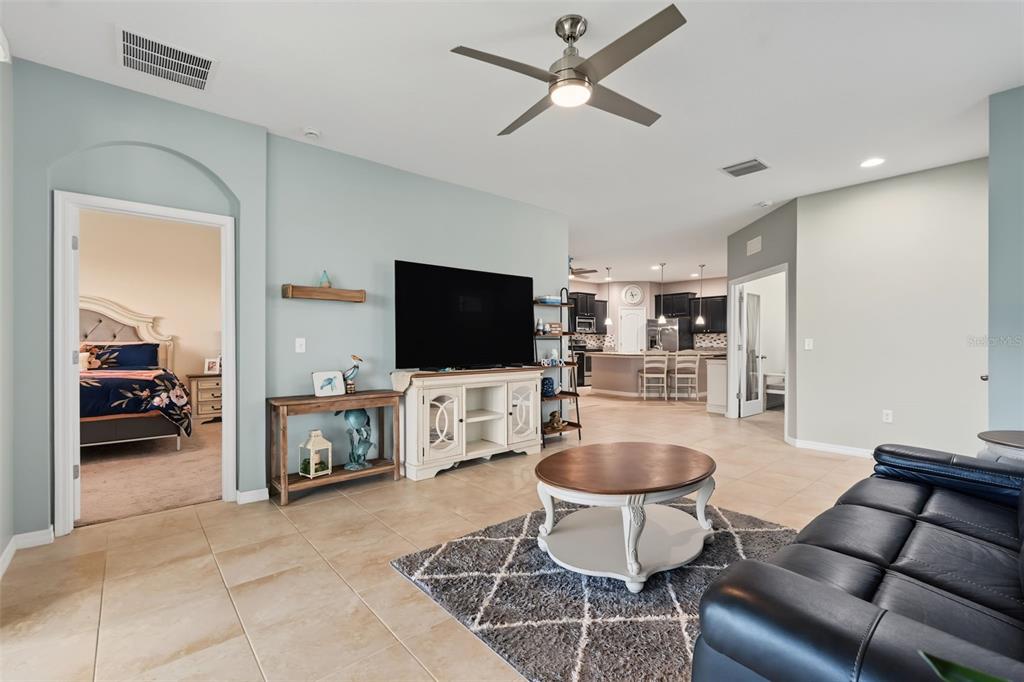 A living room with tile floors, a dark leather sofa, and sliding glass doors — 33067 WINDELSTRAW DRIVE, WESLEY CHAPEL, FL