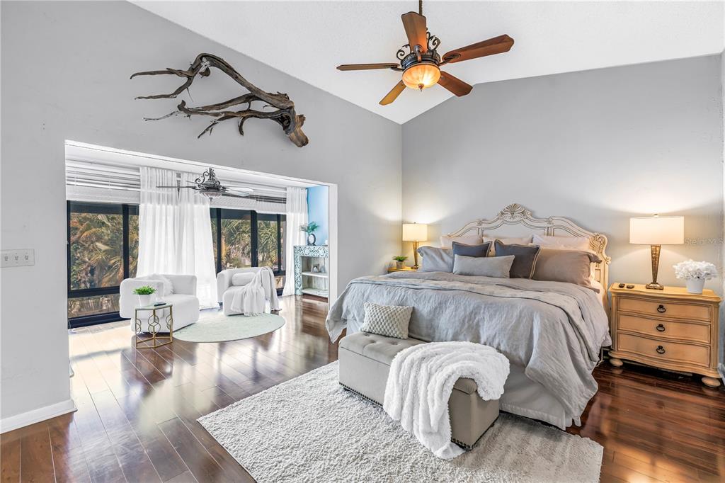 A bedroom features a large bed, a sitting area, dark wood floors, and a ceiling fan — 990 SAN CARLOS COURT NE, ST PETERSBURG, FL
