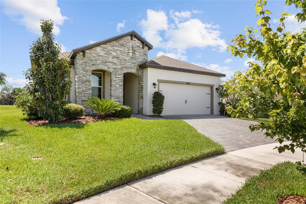 A single-story house features a stone facade, a two-car garage, and a paved driveway — 6211 SEA AIR DRIVE, APOLLO BEACH, FL