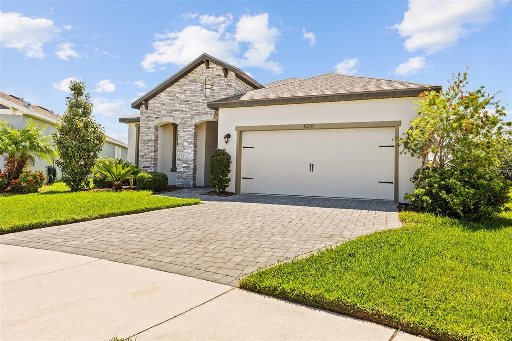A single-story house features a stone facade, a two-car garage, and a paved driveway — 6211 SEA AIR DRIVE, APOLLO BEACH, FL