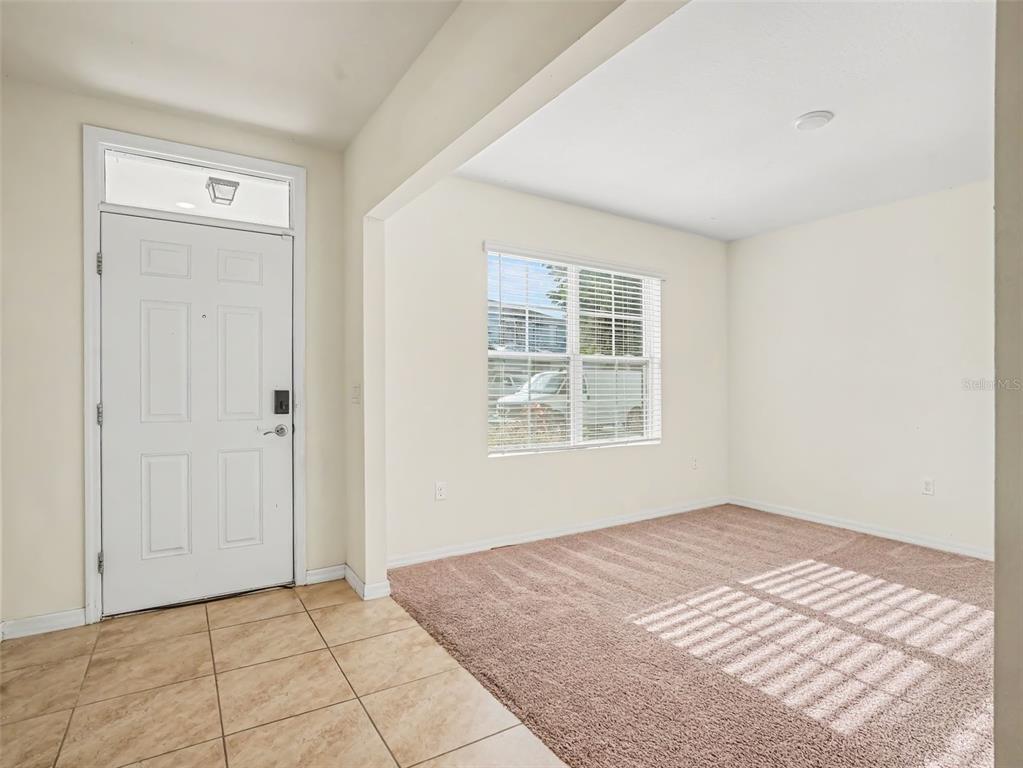 An open-concept kitchen with wood cabinets and a central island overlooks a carpeted living area — 281 ST GEORGES CIRCLE, EAGLE LAKE, FL