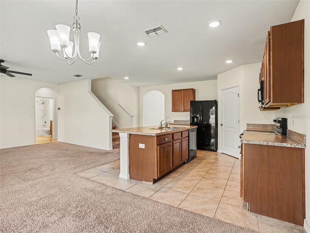 A kitchen features wood cabinets, granite countertops, and black appliances against light-colored walls — 281 ST GEORGES CIRCLE, EAGLE LAKE, FL