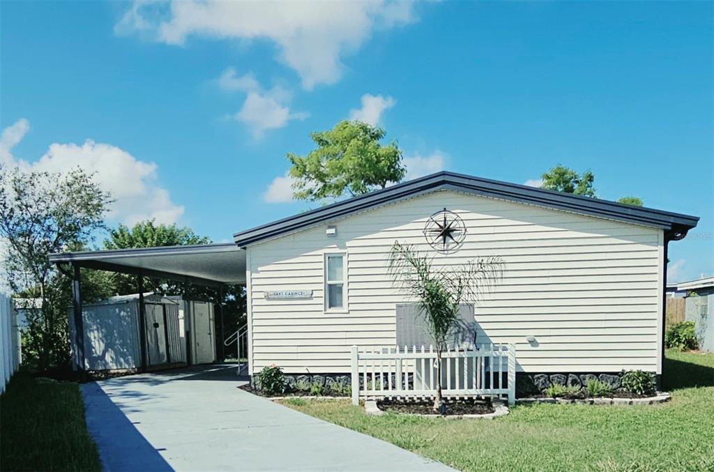 A white mobile home sits on a grassy bank overlooking a calm canal — 13147 CABIN COURT, HUDSON, FL