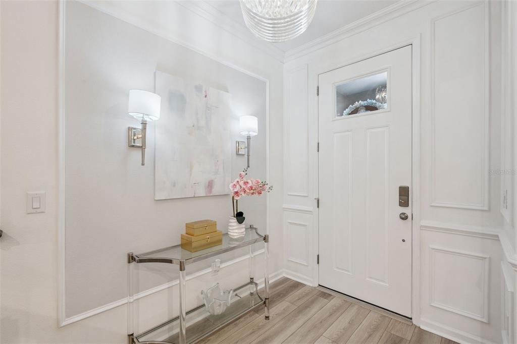 A bright entryway features a glass console table, wall sconces, and white wainscoting — 896 SPRING PALMS LOOP, ORLANDO, FL