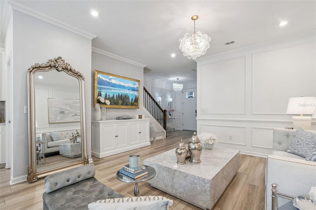 A bright living room features a marble coffee table, a large ornate mirror, and wood flooring — 896 SPRING PALMS LOOP, ORLANDO, FL