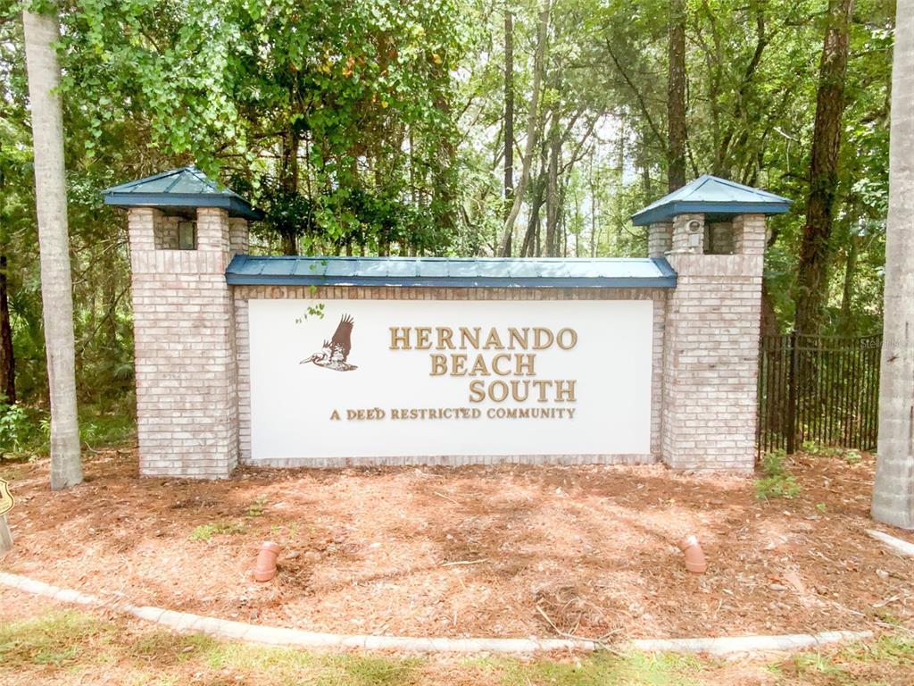 A brick entrance sign for Hernando Beach South stands in a wooded area — 3471 CROAKER DRIVE, HERNANDO BEACH, FL