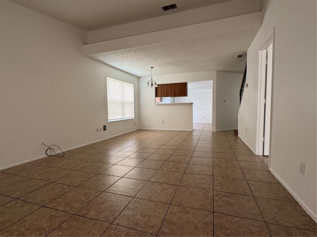 An open-concept living area features light-colored walls, tile flooring, and a pass-through to the kitchen — 2352 PEBBLE BROOK ROAD, KISSIMMEE, FL